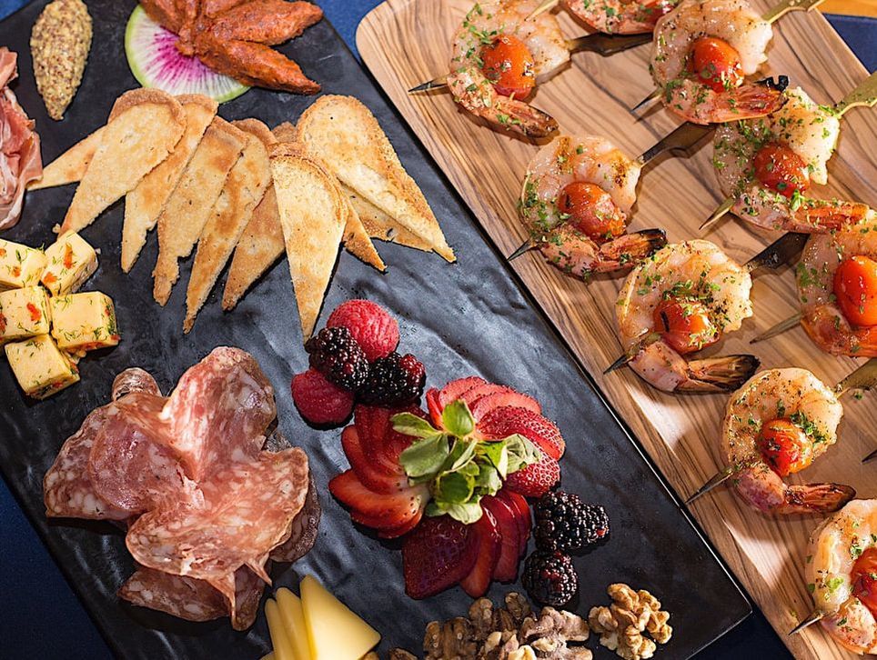 A charcuterie tray featuring shaved meats, cheeses, fruits, and seafood