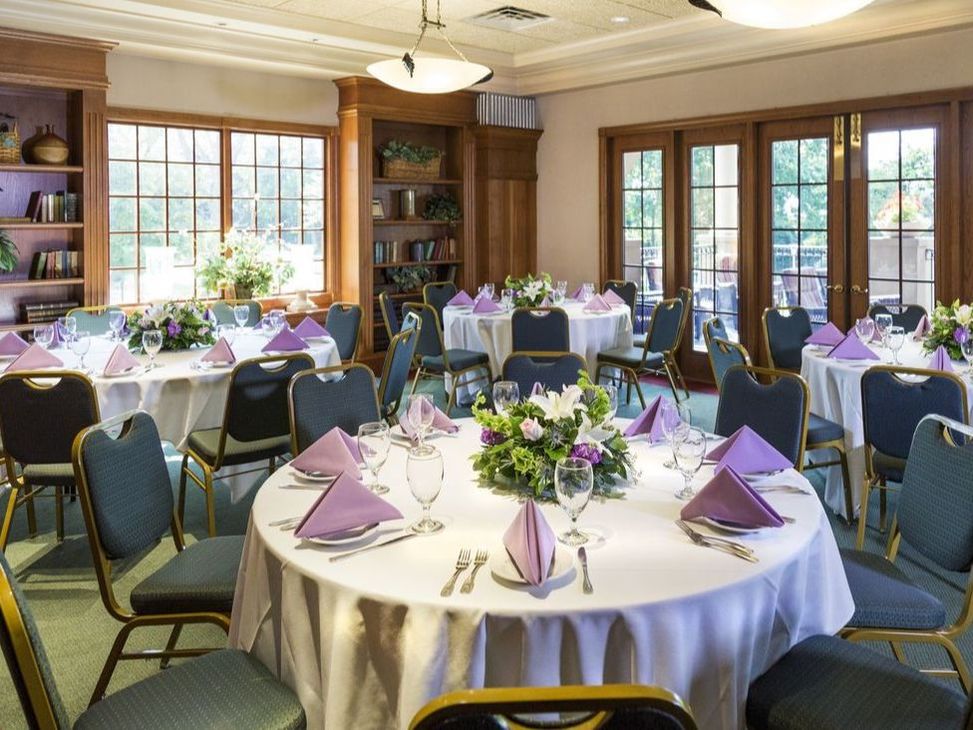 A well made banquet hall with large centerpieces and purple napkins