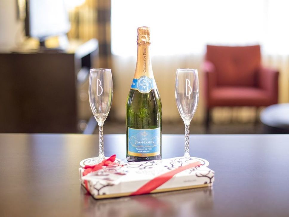 A bottle of champagne with two keepsake champagne flutes and macaroons